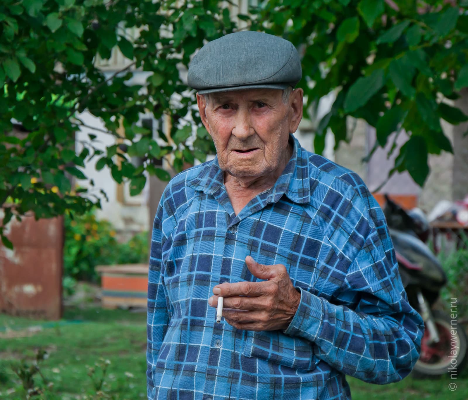 Дедушка из Верхнеадагума. В синей клетчатой рубашке, серой кепке и с сигаретой в руках